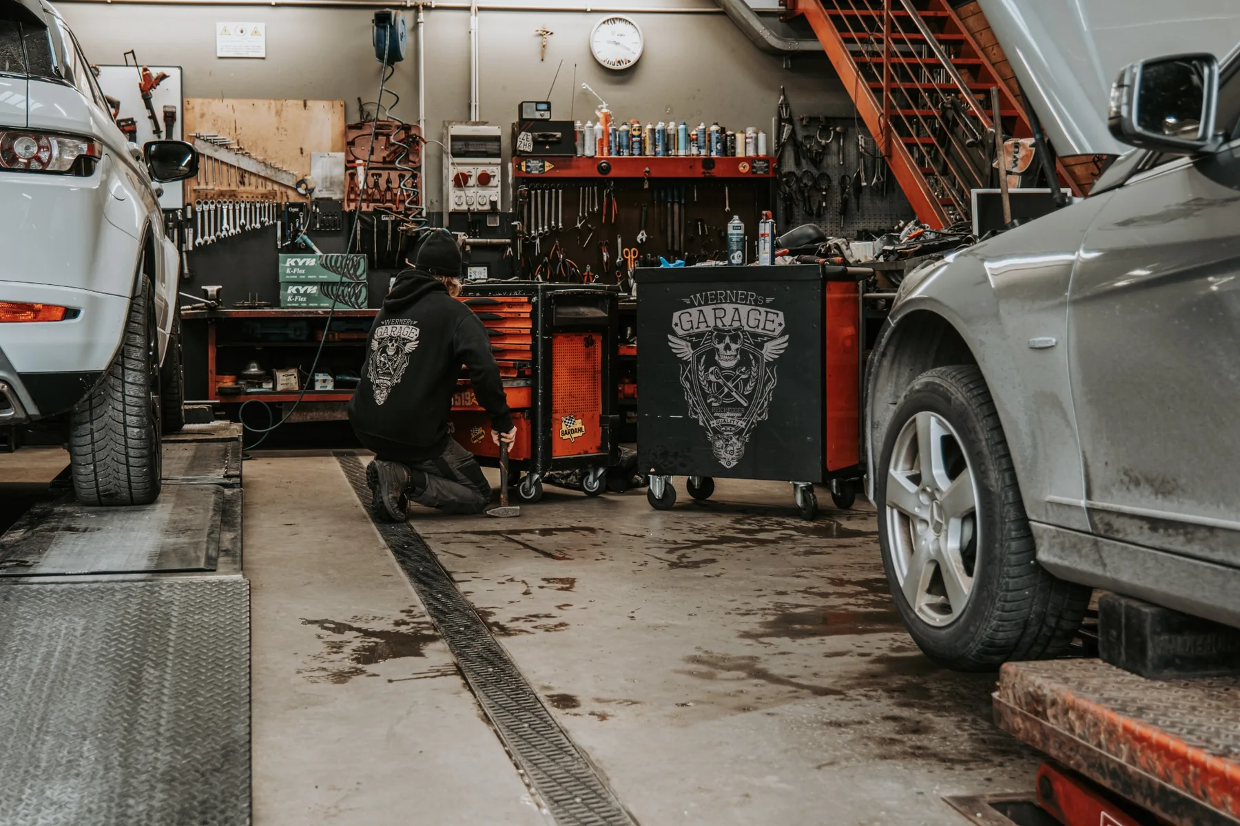 Werkstatt von Werner's Garage mit Fahrzeugen und Werkzeugwagen
